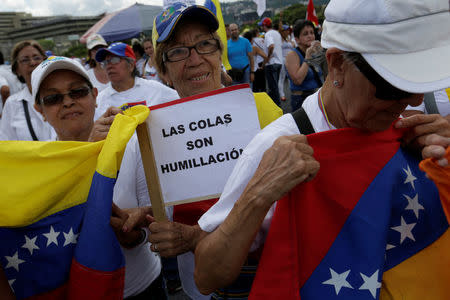 An opposition supporter holds a placard that reads "Queues are humiliation" as she takes part in a rally to demand a referendum to remove Venezuela's President Nicolas Maduro in Caracas, Venezuela October 22, 2016. REUTERS/Marco Bello