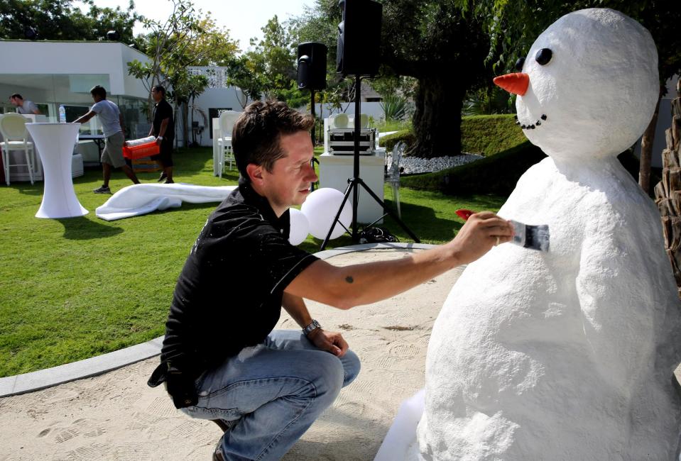 In this Saturday, Dec. 21, 2013 photo, Ben Elliott-Scott of Desert Snow company, a company which specializes in artificial snow, works on a snowman, a few hours ahead of a Christmas party at a private villa, in Dubai, United Arab Emirates. The Middle East’s brashest city is increasingly embracing the trappings of Christmas in a way that would be unthinkable in more conservative parts of the Muslim world. Christmas trees adorn shopping centers and residential neighborhoods, and high-end hotels try to outdo one another with extravagant and boozy holiday dinners. (AP Photo/Kamran Jebreili)
