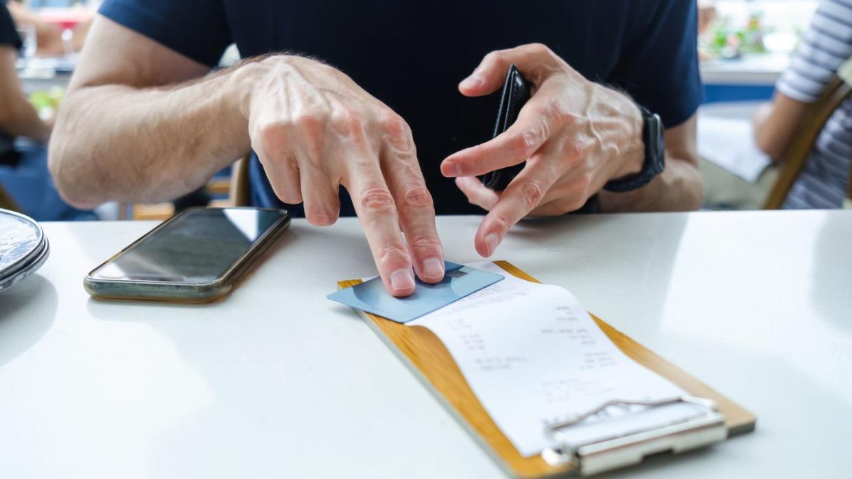 man prepares to pay restaurant bill with credit card