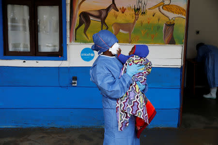 An Ebola survivor who works as a caregiver holds an infant at a United Nations Children's Fund (UNICEF) creche for children whose families are suspected or confirmed Ebola cases, near the Ebola treatment centre in Butembo in the Democratic Republic of Congo, March 26, 2019. Picture taken March 26, 2019.REUTERS/Baz Ratner