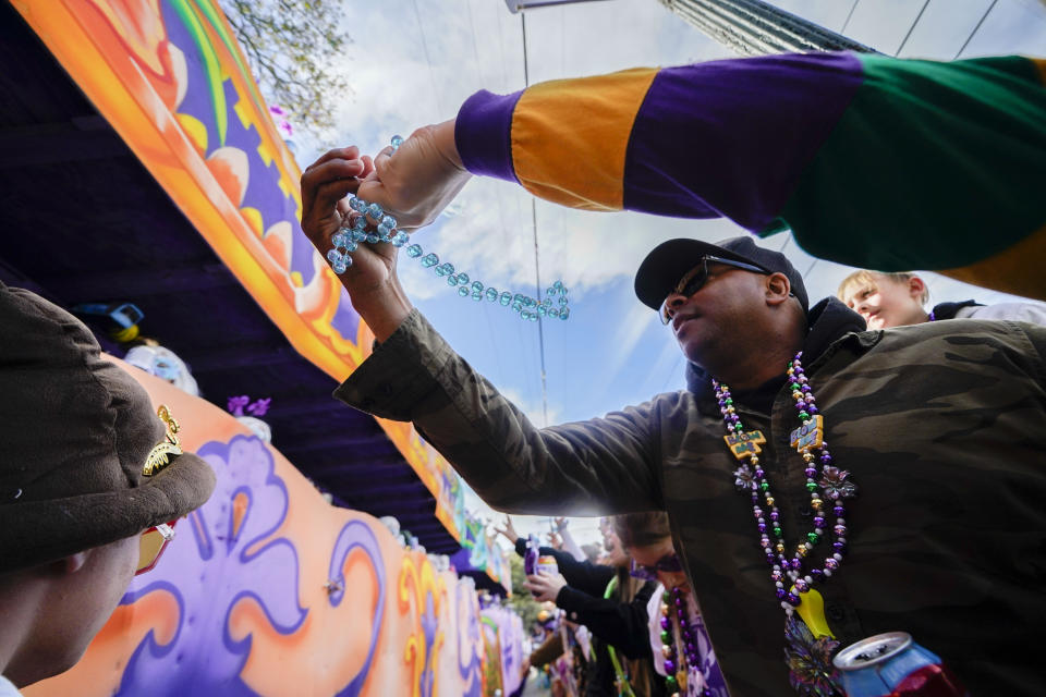 FILE - People vie for beads as the group rolls during the Krewe of Iris Mardi Gras parade in New Orleans, Saturday, Feb. 18, 2023. Mardi Gras day this year falls on Feb. 21, 2023. It’s a beloved Carnival season tradition in New Orleans — masked riders on lavish floats fling string of beads or other trinkets to parade watchers. But the huge amount of non-biodegradable plastic beads that wind up amid all the other Mardi Gras trash worries environmentalists. (AP Photo/Gerald Herbert, File)