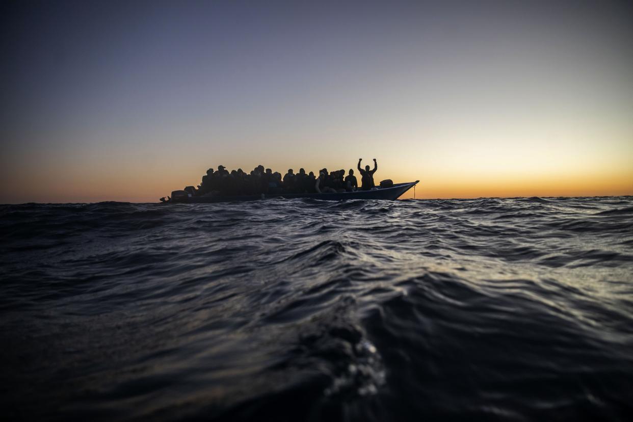 Migrants and refugees from various African countries wait for assistance on an overcrowded wooden boat on Feb. 12.