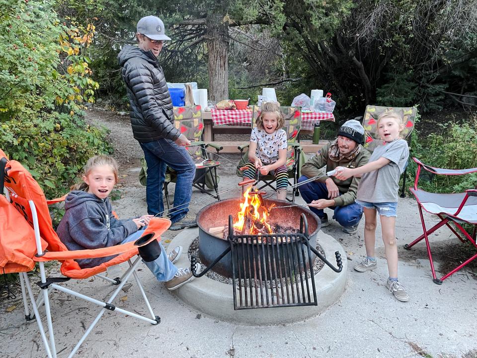 Families roasting hot dogs over fire