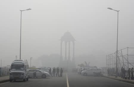 Vendors selling drinks stand beside vehicles near the India Gate war memorial on a smoggy day in New Delhi February 1, 2013. REUTERS/Adnan Abidi/Files