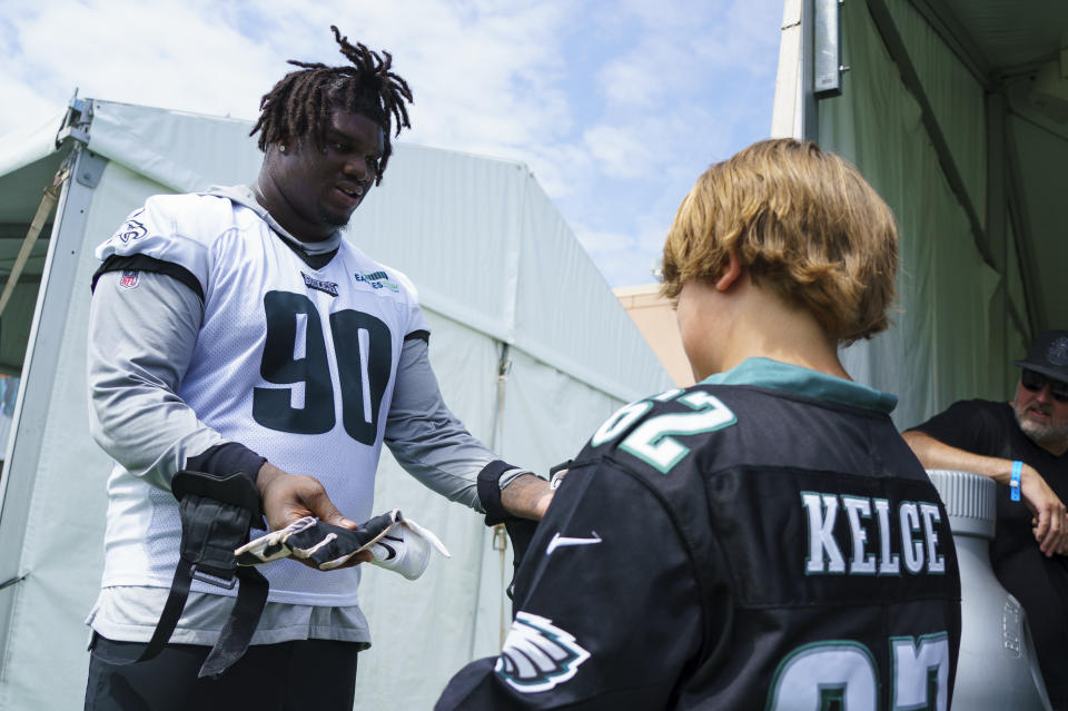 Philadelphia Eagles' Jordan Davis, left, hands his gloves to a couple of fans, right, following practice at NFL football team's training camp, Wednesday, July 27, 2022, in Philadelphia. (AP Photo/Chris Szagola)