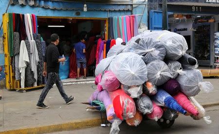 Una persona pasa junto a unos rollos de telas en el clúster textil de Gamarra en el distrito limeño de La Victoria, abr 24, 2017. Perú está ampliando su abanico de exportaciones con productos agropecuarios para reducir su dependencia de los minerales, pero aún está lejos de diversificar su economía dependiente de materias primas, una tarea de largo aliento porque requiere más inversión en infraestructura y fortalecer la industria. REUTERS/Mariana Bazo