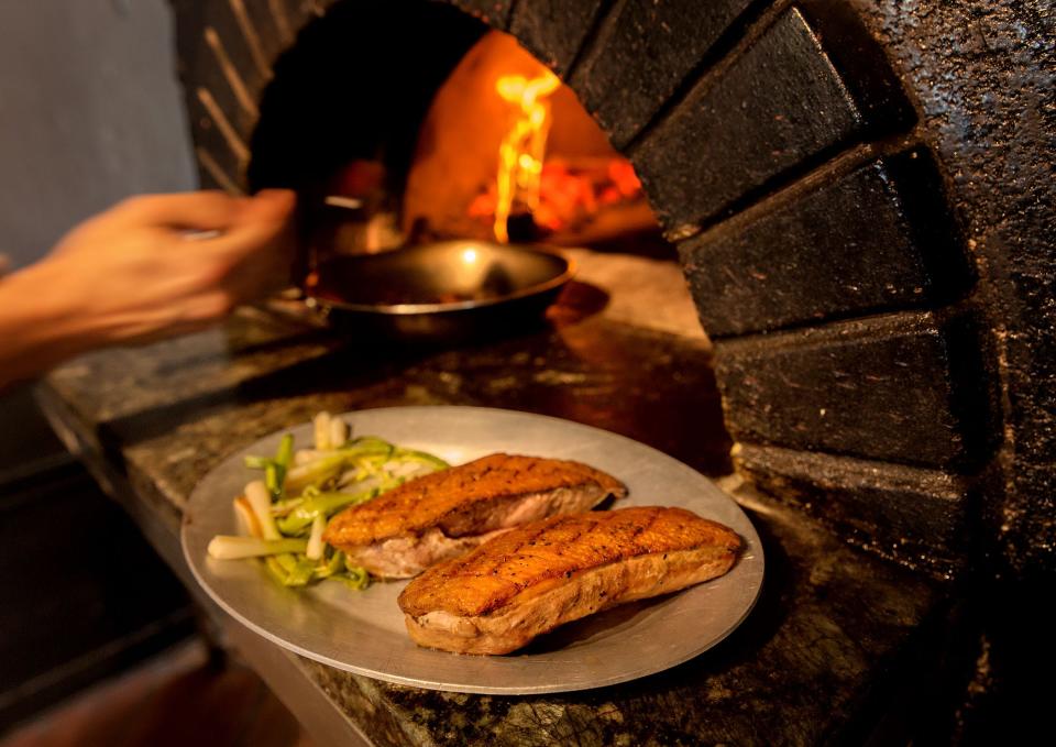 Chef Jeremy Bearman cooks bing cherry jus in the wood fired oven to pour over a dish of Long Island duck served with stone ground polenta and charred scallion at Oceano Kitchen in Lantana, June 29, 2017.