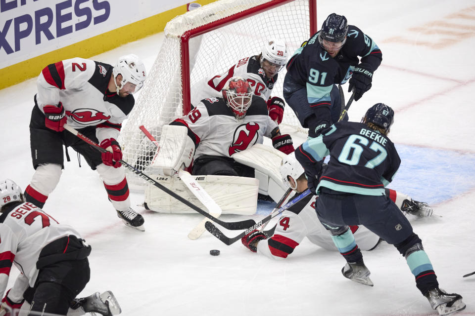 New Jersey Devils goaltender Mackenzie Blackwood (29) and defenseman Brendan Smith (2) battle to keep the puck out of the goal against Seattle Kraken center Morgan Geekie (67) and right wing Daniel Sprong (91) during the second period of an NHL hockey game, Thursday, Jan. 19, 2023, in Seattle. (AP Photo/John Froschauer)