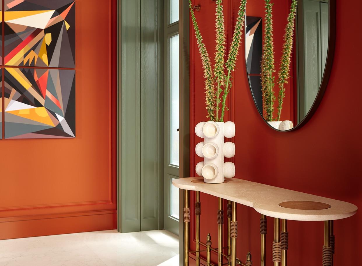  A red entryway with console table, mirror and vase 