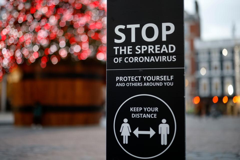 A sign promoting social distancing to combat the spread of the coronavirus is seen beside the Christmas tree in Covent Garden in central London on November 27, 2020, as life under a second lockdown continues in England. - England will return to a regional tiered system when the national stay-at-home order ends on December 2, and 23.3 million residents in the worst-hit areas are set to enter the "very high" alert level. (Photo by Tolga Akmen / AFP) (Photo by TOLGA AKMEN/AFP via Getty Images)