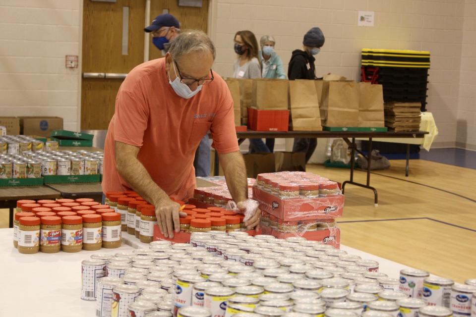 A volunteer restocks supplies during a food distribution event organized by the Christian Neighbors of Douglas on Tuesday, Nov. 23, 2021, at the Community Church of Douglas in Douglas, Mich.