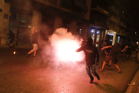 A masked demonstrator fires up the flare as others throw stones to riot police during a rally marking four years since the fatal stabbing of Greek anti-fascism rapper Pavlos Fyssas by a supporter of the ultranationalist Golden Dawn party in Athens, Greece, September 16, 2017. REUTERS/Alkis Konstantinidis