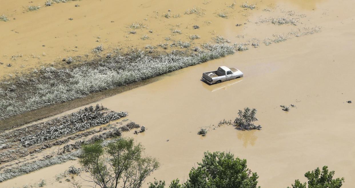 In this aerial photo, some homes in Breathitt County, Ky., are still surrounded by water on Saturday, July 30, 2022, after historic rains flooded many areas of Eastern Kentucky killing multiple people. A thin film of mud from the retreating waters covers many cars and homes.