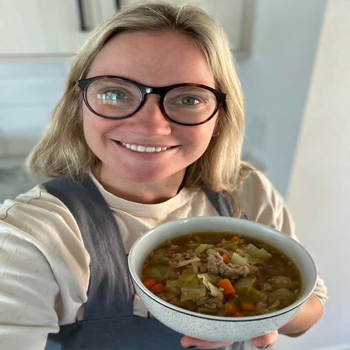 author holding up bowl of egg roll soup