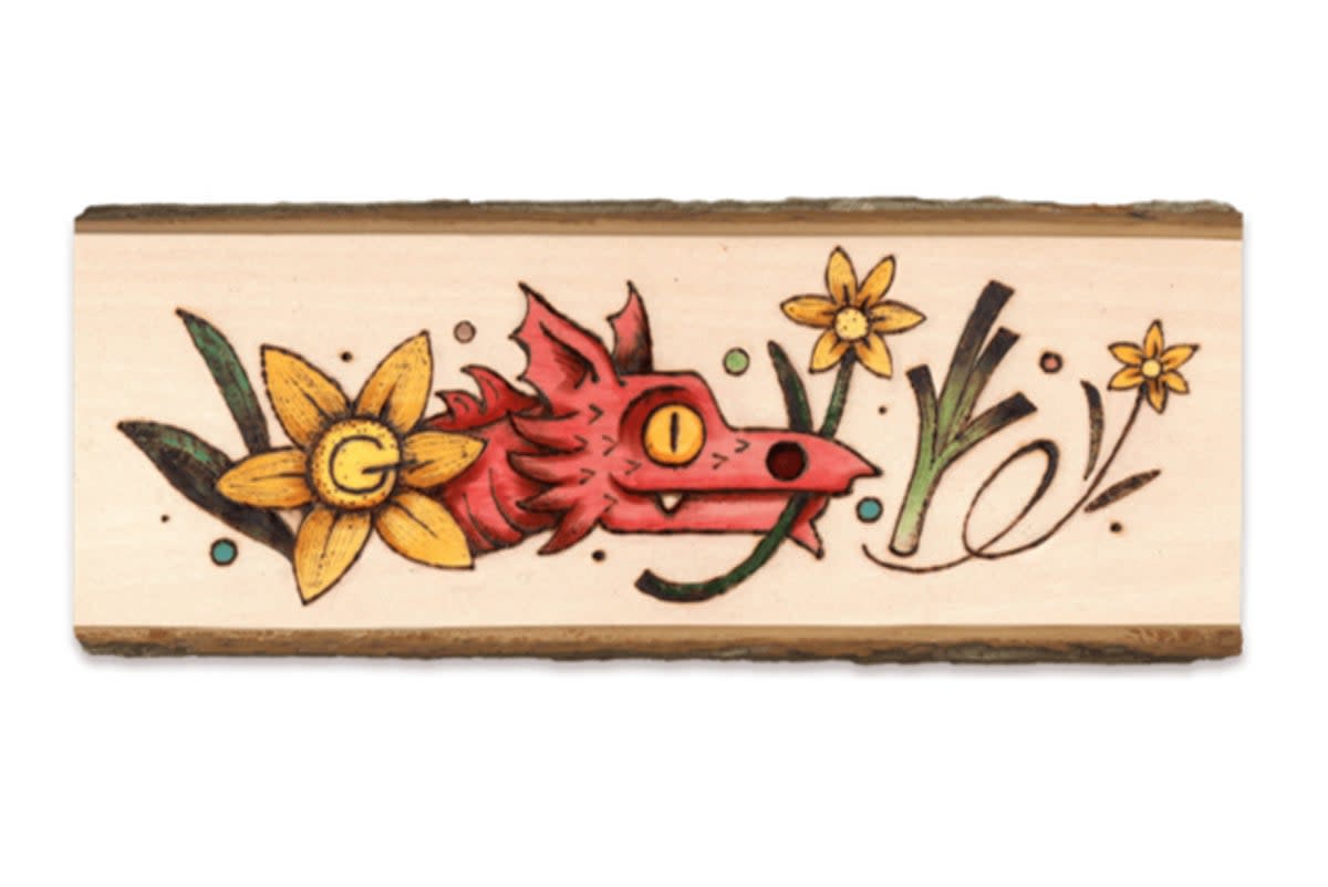The doodle depicts a Welsh red dragon holding a daffodil and includes a leek  (Google Doodle)