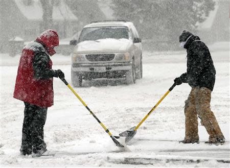 Workers team up to clear a sidewalk during a blizzard in Mission, Kansas, February 4, 2014. REUTERS/Dave Kaup