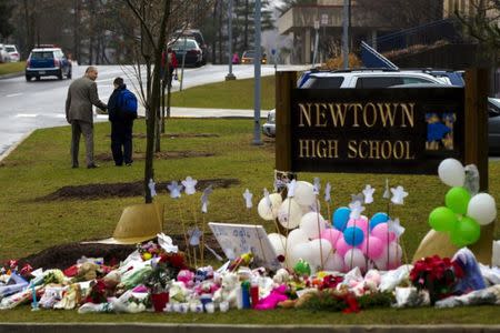 A student is consoled after he placed flowers on a memorial at the entrance to Newtown High School in Newtown, Connecticut December 18, 2012. REUTERS/Lucas Jackson