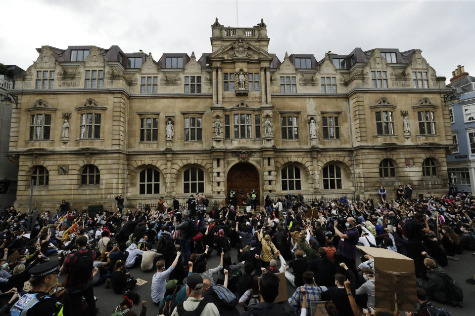 FILE - In this file photo dated Tuesday, June 9, 2020, supporters of the Rhodes Must Fall group, participate in a protest calling for the removal of a statue of Cecil Rhodes, a Victorian imperialist in southern Africa who made a fortune from mines and endowed the university's Rhodes scholarships, beneath the statue which stands on the facade, top centre, of Oriel College, in Oxford, England. The death of George Floyd at the hands of police and Minneapolis, USA, has sparked a re-examination of injustices and inequalities in the fabric of many societies, often symbolized in statues of historical figures have become the focus of protest around the world. (AP Photo/Matt Dunham, FILE)