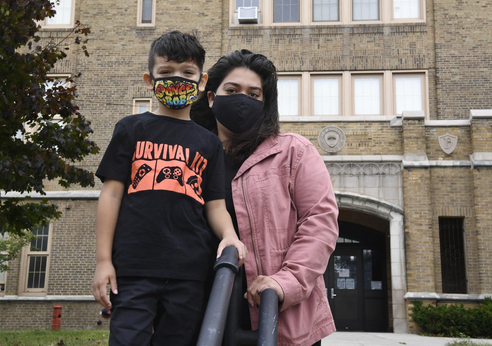 Kristina Negron poses for a photograph with her son, Mason Negron, 6, at his Pleasant Valley Elementary school Tuesday, Sept. 29, 2020, in Schenectady, N.Y. Negron was laid off from her job as an aide for a special education class at Schenectady High School, due to budget cuts. (AP Photo/Hans Pennink)