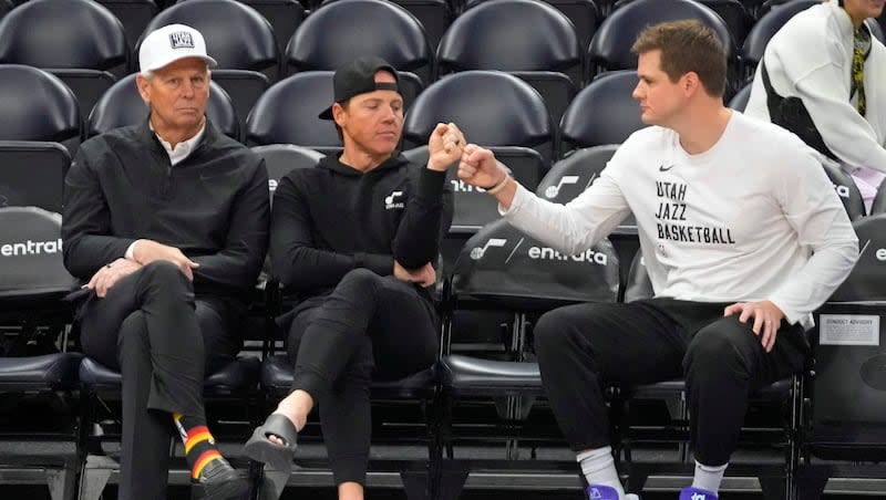 Utah Jazz's CEO, Danny Ainge, left, looks on as Jazz owner Ryan Smith and head coach Will Hardy fist bump while sitting court side before the start an NBA basketball game against the Oklahoma City Thunder Tuesday, Feb. 6, 2024, in Salt Lake City. (AP Photo/Rick Bowmer)