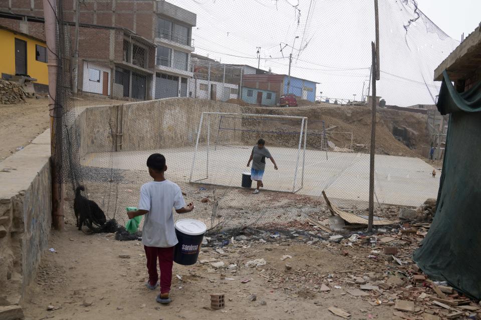 Residentes llevan cubos llenos de excrementos humanos mezclados con aserrín, como parte del programa de saneamiento alternativo, en el barrio de Pamplona Alta de Lima, Perú, el miércoles 20 de marzo de 2024. El servicio incluye el reparto de aserrín, la instalación del baño seco y el traslado de los desechos hacia un contenedor que semanalmente lleva 40 toneladas a un relleno sanitario. (AP Foto/Martín Mejía)