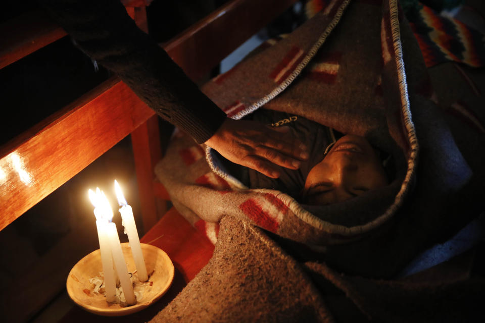 A mourner places a hand on the shoulder of Devi Posto killed during clashes between security forces and supporters of former President Evo Morales, during a vigil at the San Francisco de Asis church in El Alto, on the outskirts of La Paz, Bolivia, Wednesday, Nov. 20, 2019. The death toll from an operation by Bolivian security forces to clear the blockade of a fuel plant by anti-government protesters has risen to six the public defender’s office announced Wednesday.(AP Photo/Natacha Pisarenko)