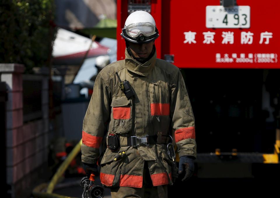 A firefighter walks out from the site where a light plane went down in a residential area and burst into flames, in Chofu