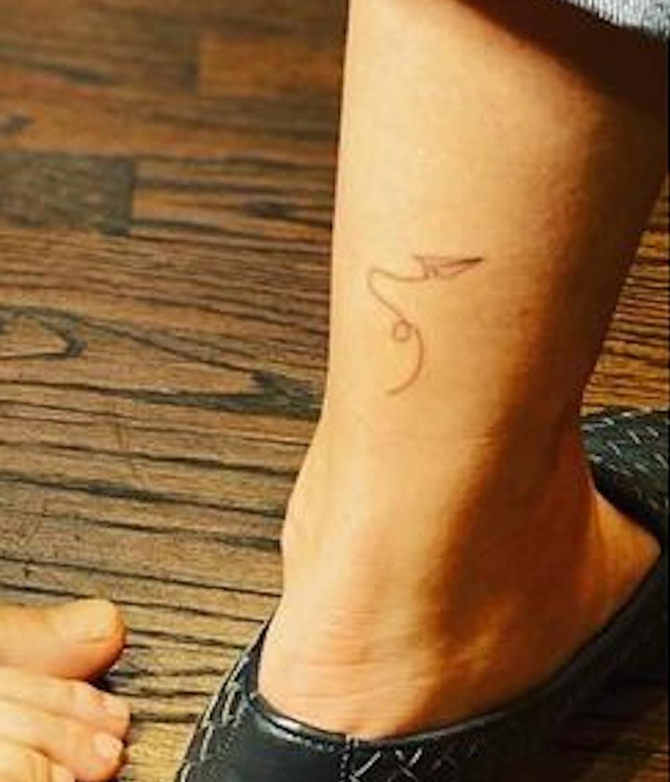 A paper airplane tattoo seen on actress Kaley Cuoco's lower calf, just above her ankle.