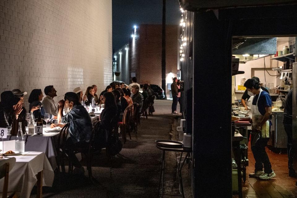 Customers fill Anajak Thai's alleyway tables, left,; a chef cooks in the kitchen