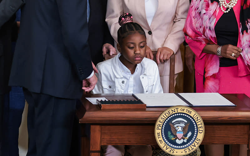 George Floyd's daughter, Gianna Floyd, looks down at an executive order on a presidential podium