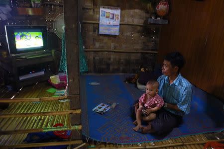 A man and his child watch TV in their home at Kanhla village, an area to be included in the New City Project, outside Yangon August 30, 2014. REUTRS/Soe Zeya Tun