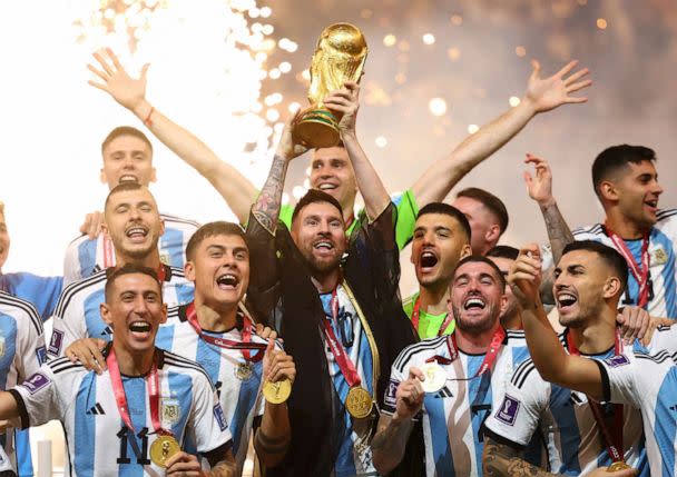 PHOTO: Argentina's Lionel Messi lifts the World Cup trophy alongside teammates as they celebrate after winning the World Cup, Dec. 18, 2022, in Lusail, Qatar. (Kai Pfaffenbach/Reuters)