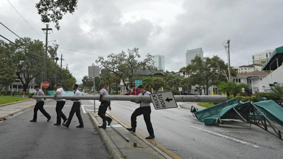 Members of the Tampa Fire Rescue Dept., remove a street pole after large awnings from an apartment building blew off from winds associated with Hurricane Idalia Wednesday, Aug. 30, 2023, in Tampa, Fla. Idalia made landfall earlier this morning along the Big Bend of the state. (AP Photo/Chris O'Meara)