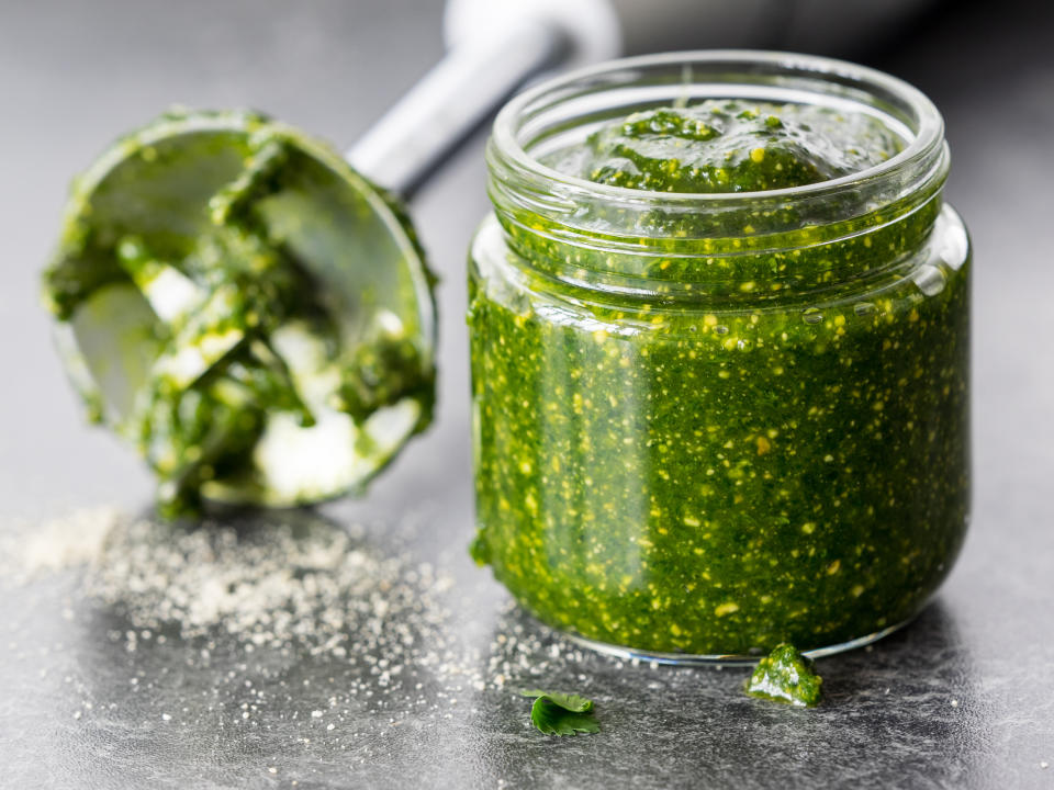 basil pesto in a glass jar with a blender in the background