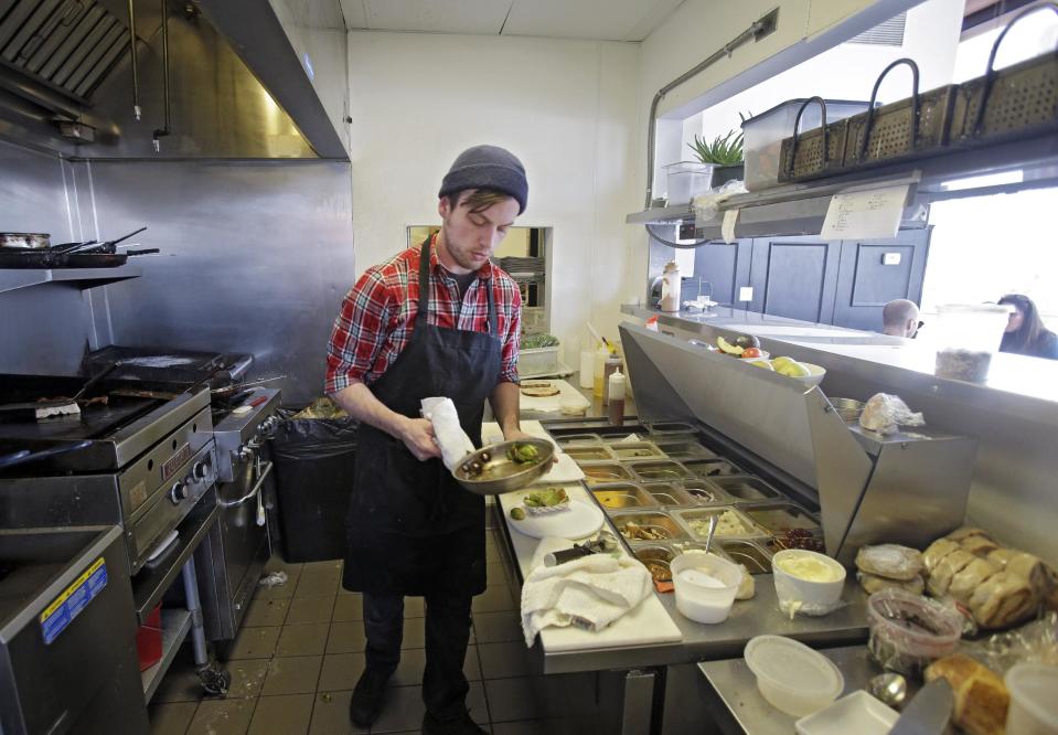 In this Tuesday, Jan. 28, 2014 photo, cook Joe Egar plates an order at Bonbon Pastry and Cafe in Cleveland. Single-digit temperatures across the U.S. and record snowfalls in the Midwest since the beginning of January have put the freeze on businesses that rely on walk-ins and appointments. At the cafe in the city's Market Square district, this past weekend was especially slow with whiteout conditions making going outside unappealing for customers. (AP Photo)