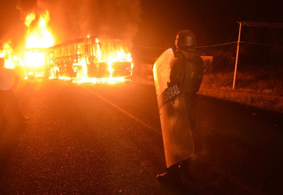 A police officer watches a burning bus after clashes with students involved in campus takeovers in Tiripetío, Michoacan state, Mexico, Monday, Oct. 15, 2012. Police raided three teachers colleges on Monday in the western state of Michoacan, where dozens of students had been hijacking buses and delivery trucks for a week to protest curriculum changes. (AP Photo)