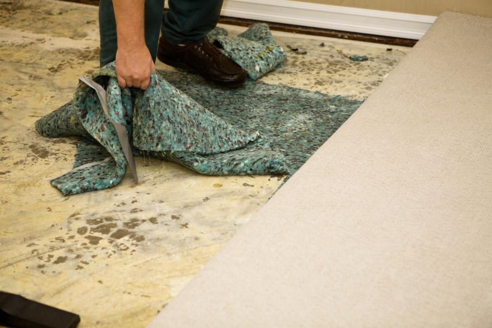 A close up of a person peeling back a carpet. 