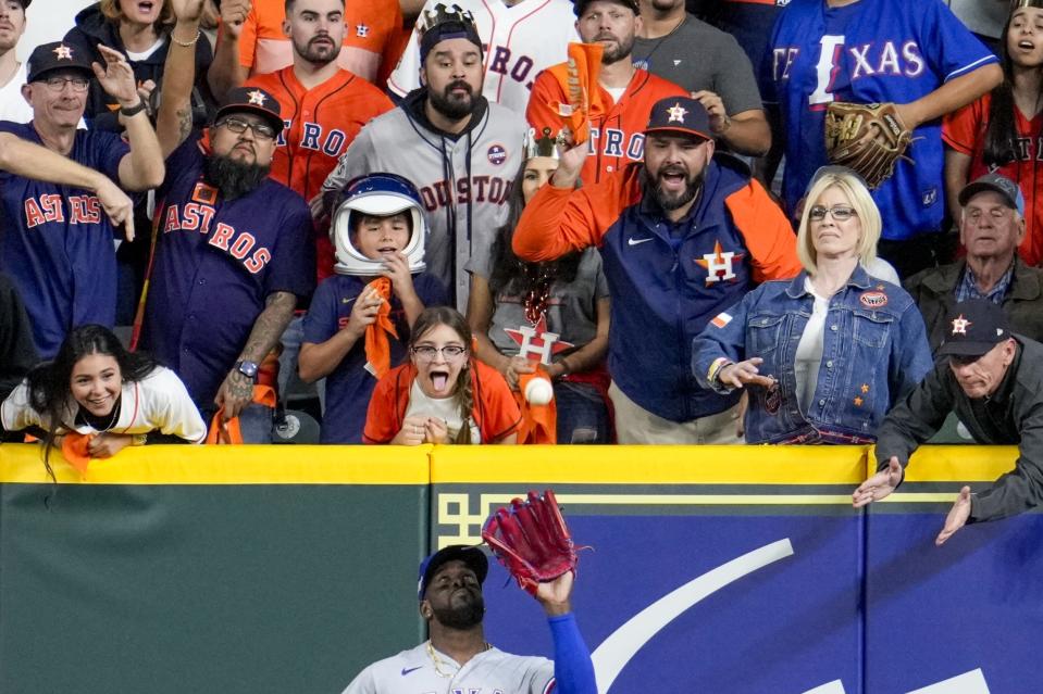 Fans try to distract Texas Rangers' Adolis Garcia as he catches a ball hit by Houston Astros' Jeremy Pena during the ninth inning of Game 2 of the baseball AL Championship Series Monday, Oct. 16, 2023, in Houston. (AP Photo/Godofredo A. Vasquez)