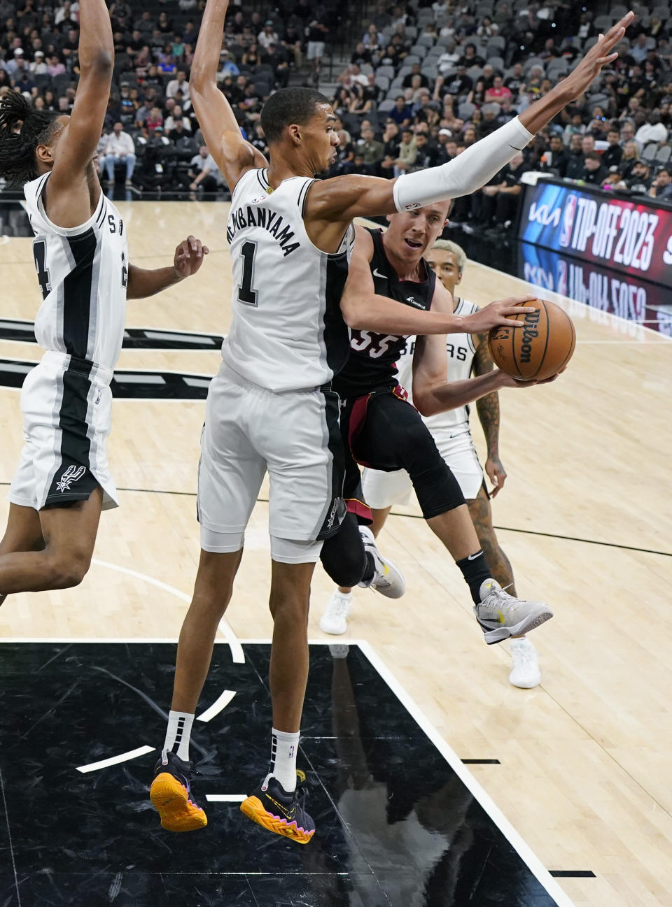 Miami Heat forward Duncan Robinson (55) drives to the basket against San Antonio Spurs center Victor Wembanyama (1) during the first half of a preseason NBA basketball game in San Antonio, Friday, Oct. 13, 2023. (AP Photo/Eric Gay)