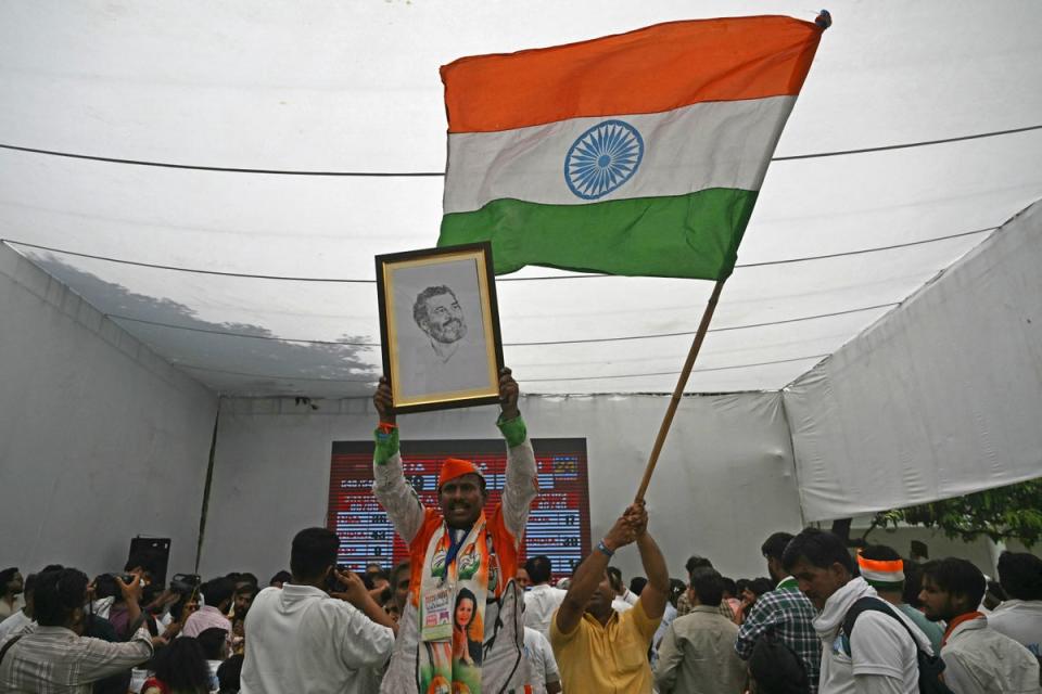Supporters of the Congress party hold a portrait of Rahul Gandhi and wave India’s national flag after the votes were counted in India’s national election, in Delhi on 4 June 2024 (AFP via Getty)