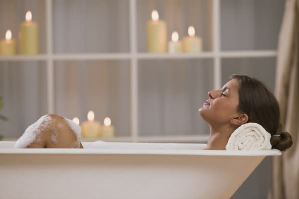 Woman relaxing in bath with candles