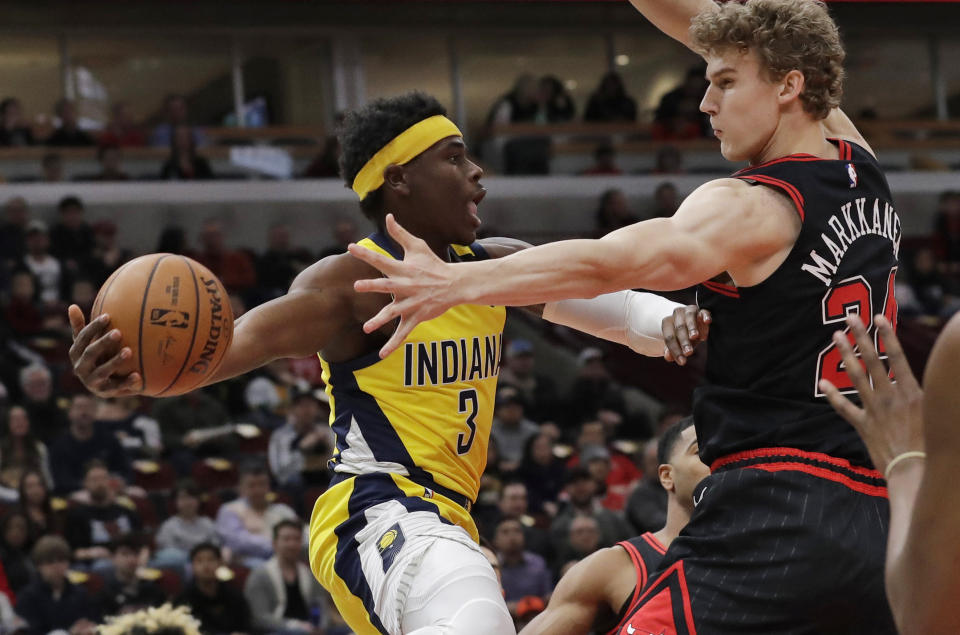 Indiana Pacers guard Aaron Holiday, left, looks to pass the ball as Chicago Bulls forward Lauri Markkanen defends during the first half of an NBA basketball game in Chicago, Friday, March 6, 2020. (AP Photo/Nam Y. Huh)
