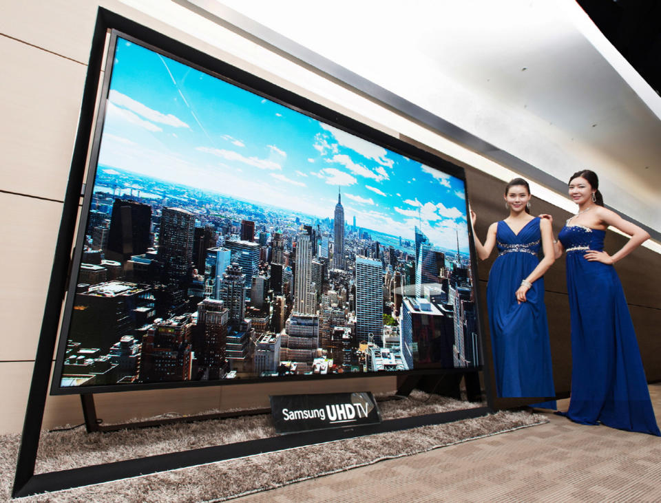 In this undated handout photo released by Samsung Electronics Co. Monday, Dec. 30, 2103, models pose with a Samsung Electronics' 110-inch UHD TV. Samsung on Monday said a 110-inch UHD TV that has four times the resolution of standard high-definition TVs is going on sales for about $150,000 in South Korea. (AP Photo/Samsung Electronics Co.)