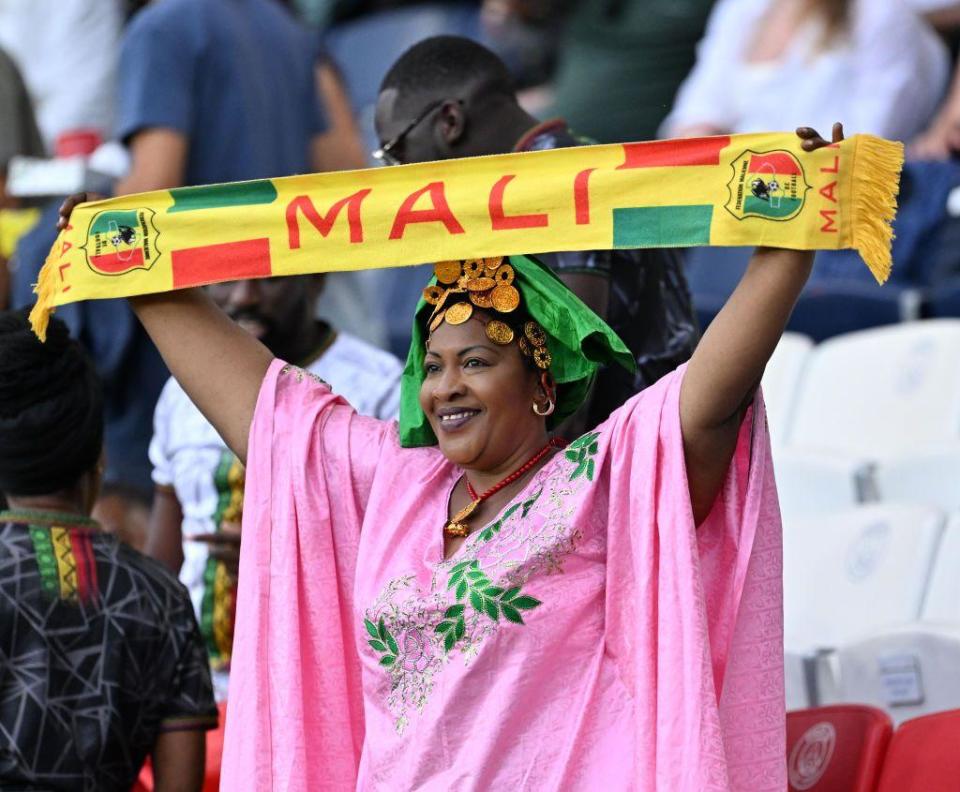 A woman in a pink dress waves a Malian flag at a stadium in Paris, France - Thursday, July 25, 2024