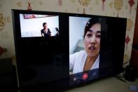Bi Fenghua, 66, and her daughter-in-law are seen on the screen of a TV set as she performs the video chat function provided by Lanchuang's elderly care system in Weifang