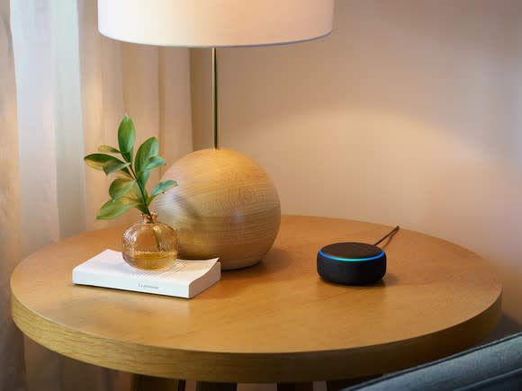 Echo Dot device on a side table, next to a lamp and a small vase.