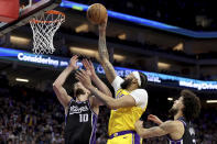 Los Angeles Lakers forward Anthony Davis, center, shoots against Sacramento Kings forward Domantas Sabonis (10) and guard Chris Duarte, right, during the first half of an NBA basketball game in Sacramento, Calif, Wednesday, March 13, 2024. (AP Photo/Jed Jacobsohn)