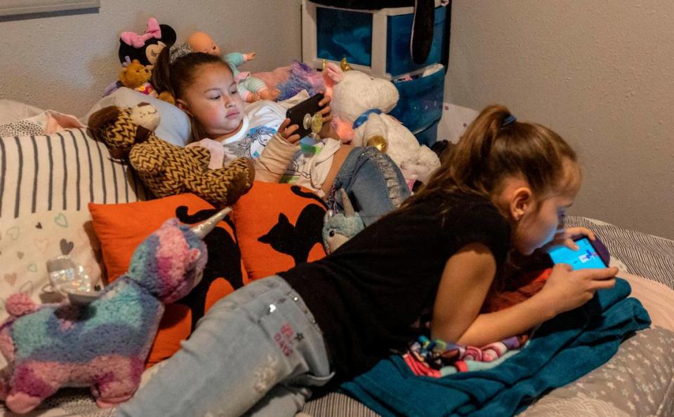 Rozay, 7, and her sister Lyric, 8, play games on their parents’ phones.