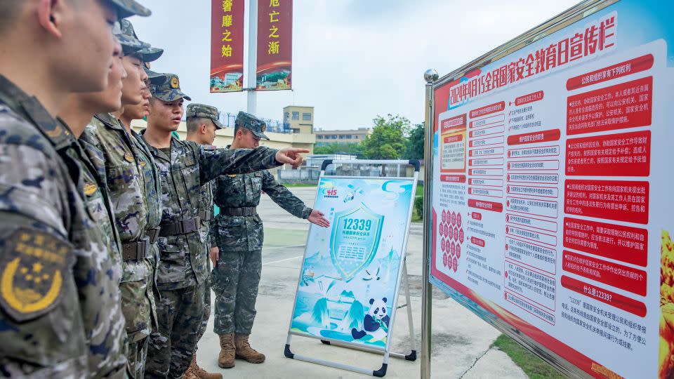 Chinese soldiers look at a poster promoting national security in the southwestern city of Beihai on National Security Education Day on April 15, 2024. - CFOTO/Future Publishing/Getty Images