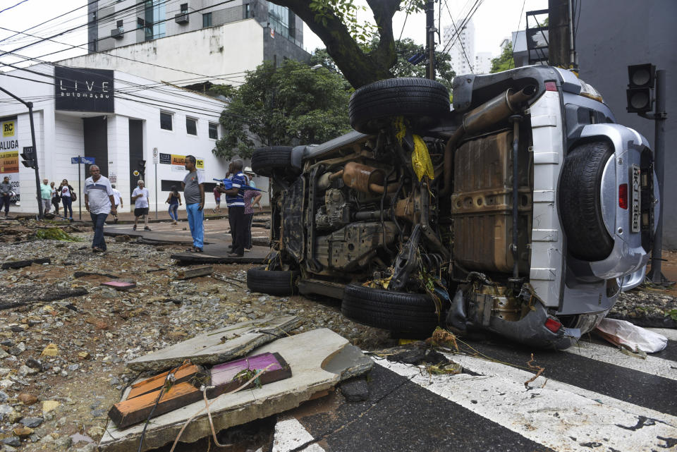 A car that was swept away by floods lays on its side in Belo Horizonte, Minas Gerais state, Brazil, Wednesday, Jan. 29, 2020. Heavy rains devastated the Brazilian state of Minas Gerais on Tuesday night and Wednesday morning, causing destructive flooding and landslides. (AP Photo/Gustavo Andrade)